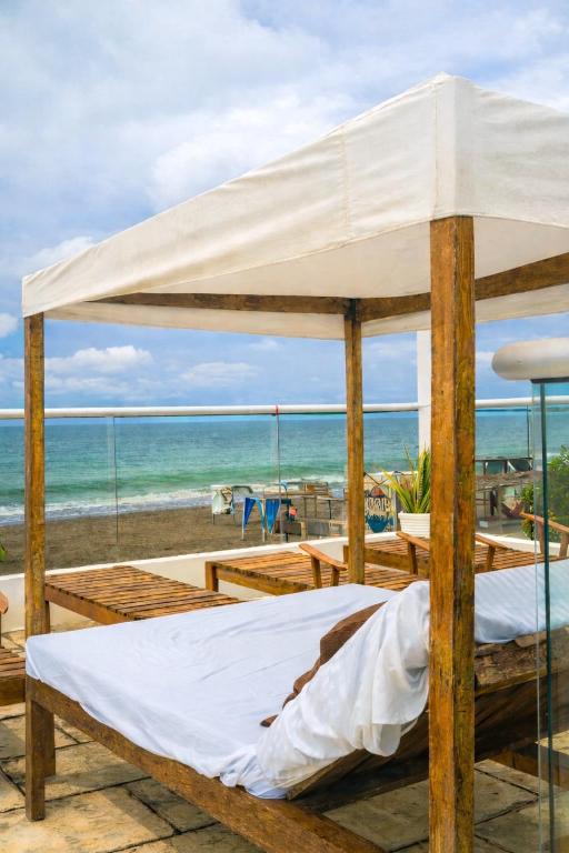 a bed with a canopy on the beach at Open Sea Hotel Cartagena - Frente al mar in Cartagena de Indias