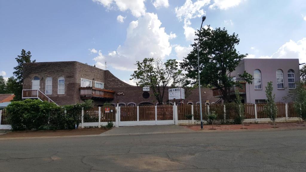a brick house with a white fence in front of it at Like a Rock in Bloemfontein
