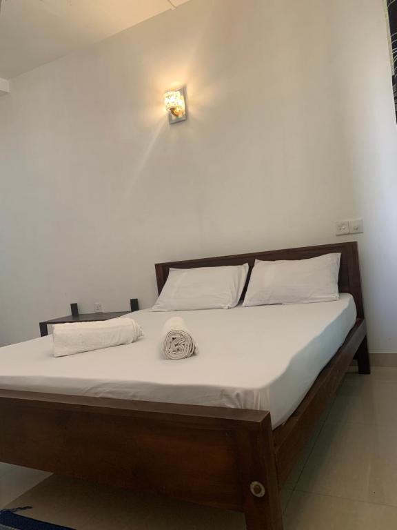 a bed with white sheets and a light on the wall at New Papa Palace in Wattegama