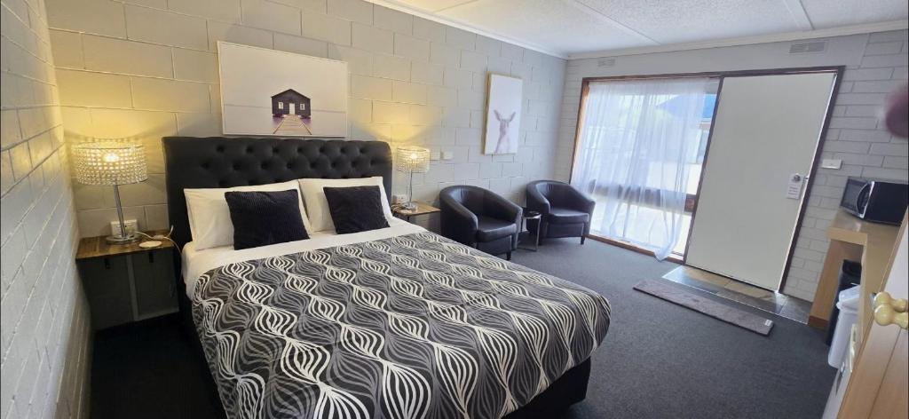 a bedroom with a bed and two chairs and a window at Mariner Motel in Portland