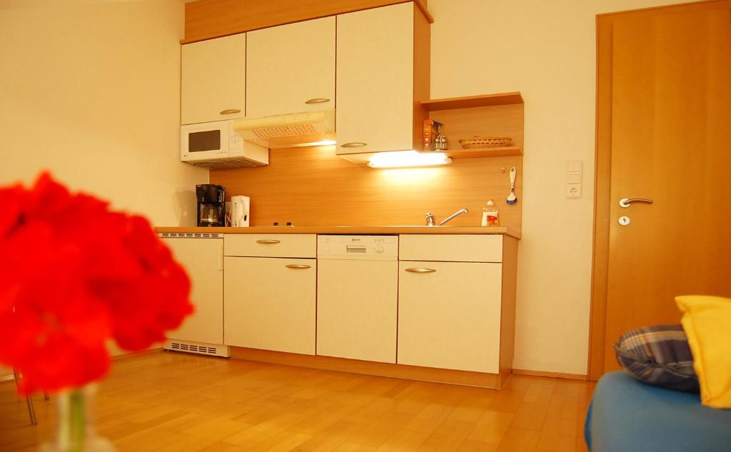 a kitchen with white cabinets and a vase of red flowers at Haus Blankus in Brand