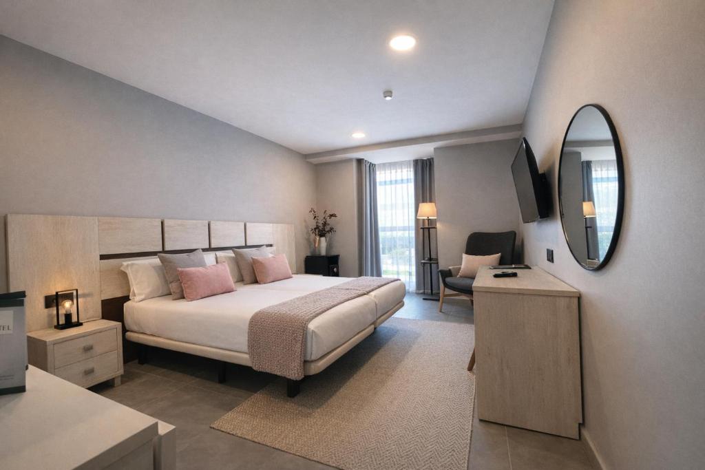 a bedroom with a large bed and a mirror at Apartahotel 5dos5 in Oviedo