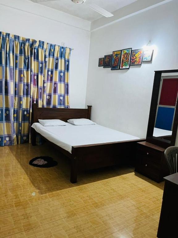 a bedroom with a bed and a dresser and curtains at Aluvihare Residence in Matale