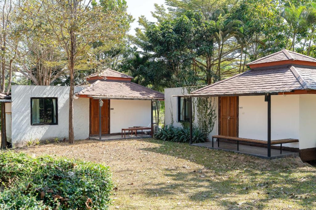 two buildings with benches in a yard with trees at De Bua Valley Resort in Wang Nam Khieo
