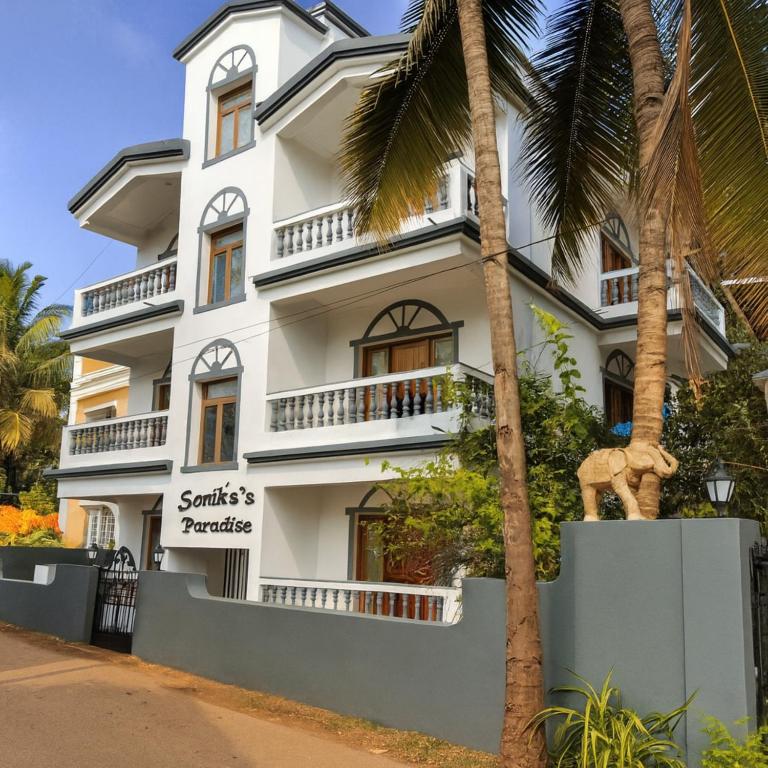 a white building with a sign in front of it at Sonika's Paradise (Studio) in Candolim