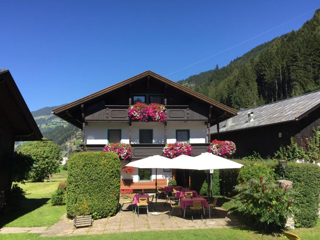a house with tables and chairs and an umbrella at Gasthof Waldrast in Zell am Ziller
