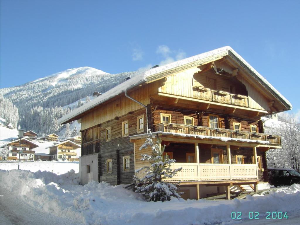 ein großes Holzgebäude mit Schnee auf dem Boden in der Unterkunft Ferienhaus Schett in Innervillgraten