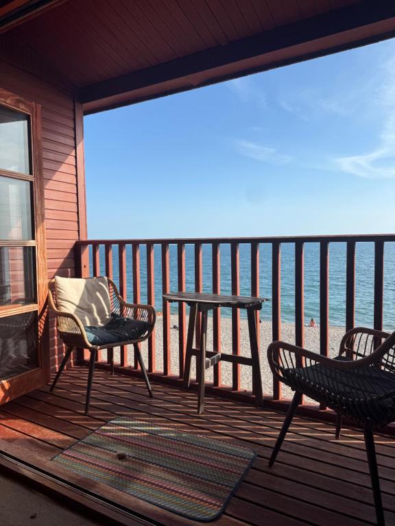a patio with a table and chairs on a balcony at Branscombe Chalet on the Beach in Branscombe