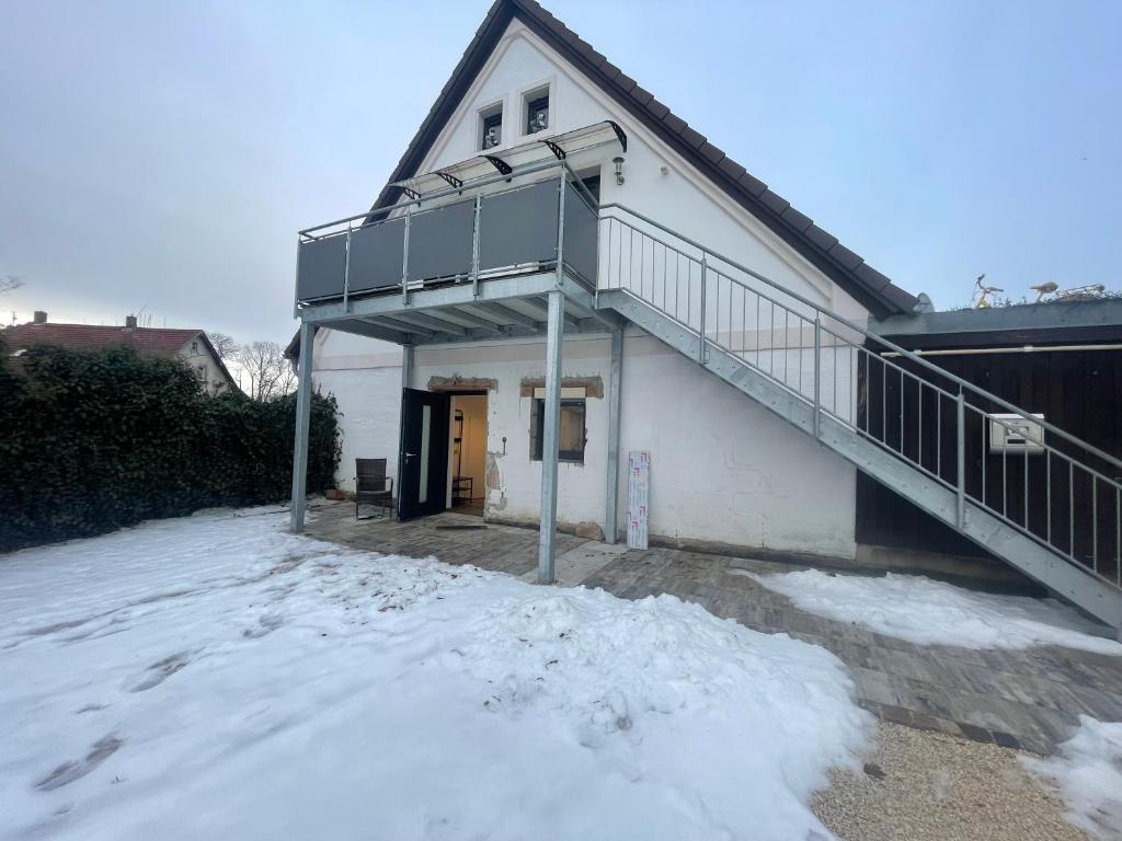 a house with a balcony and a staircase in the snow at OK-City in Bayreuth