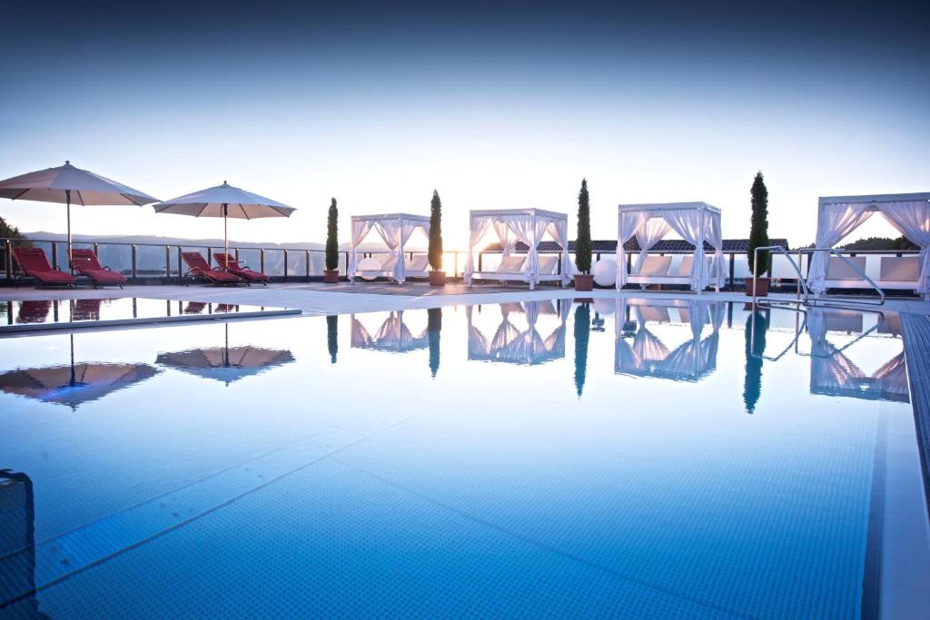 a swimming pool with chairs and umbrellas in a resort at Wellnesshotel Oswald in Kaikenried