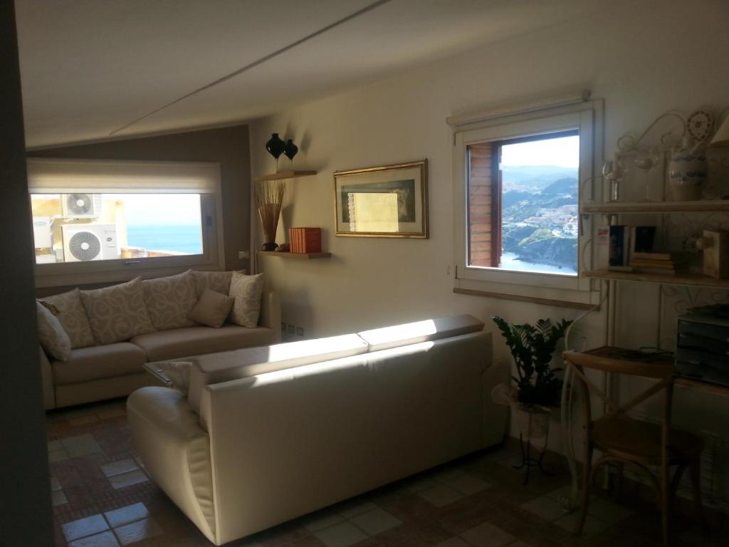 een woonkamer met een bank en 2 ramen bij Appartamento mansardato Anda&Torra in Castelsardo