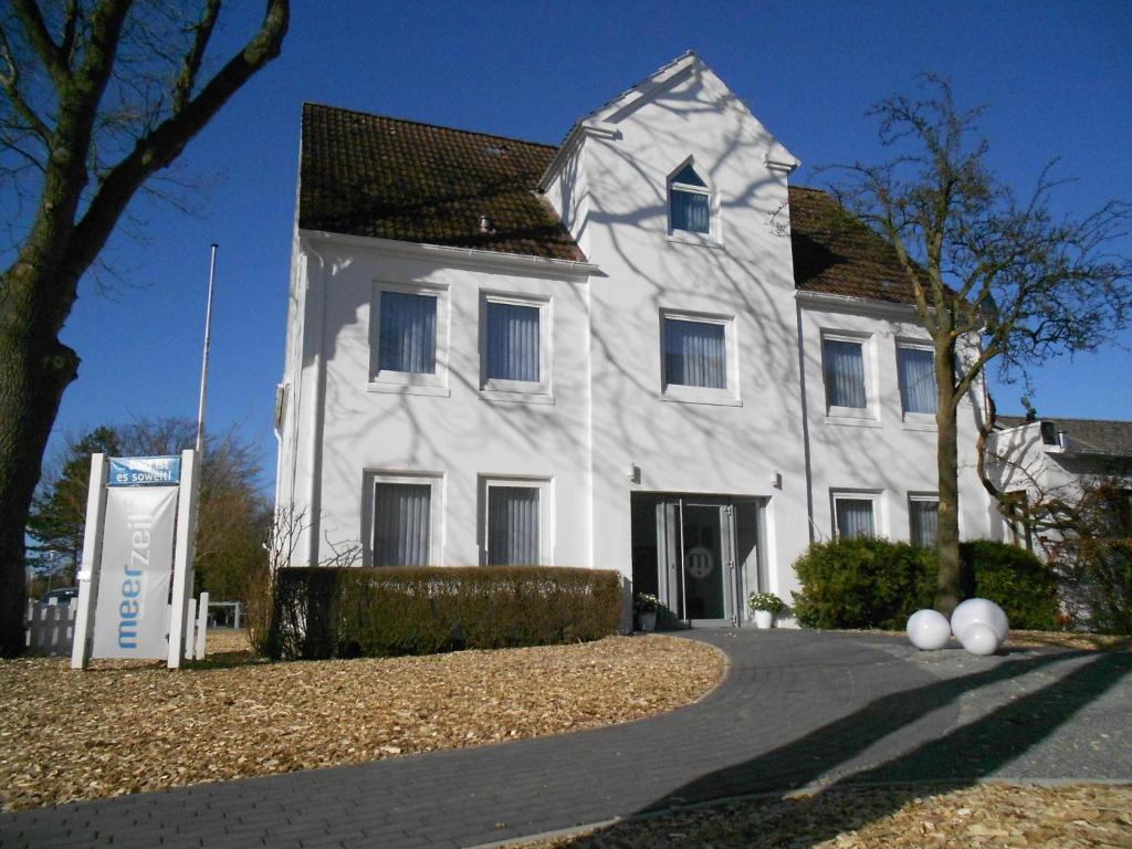 a white house with a sign in front of it at meerzeit Hotel in Cuxhaven