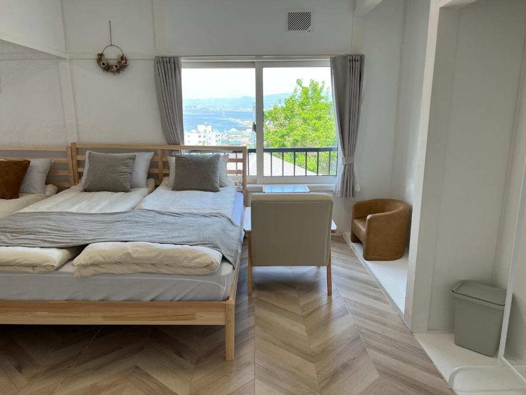 a bedroom with two beds and a large window at Local Stay Hakodate in Hakodate