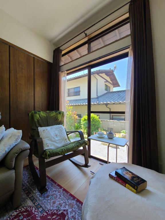 a bedroom with a bed and a chair and a window at Daizaifu Guest House 1 in Dazaifu