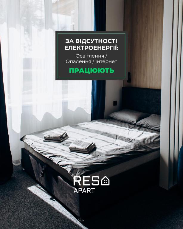 a bed in a room next to a window at RESA apart - нові smart-квартири біля річки in Uzhhorod