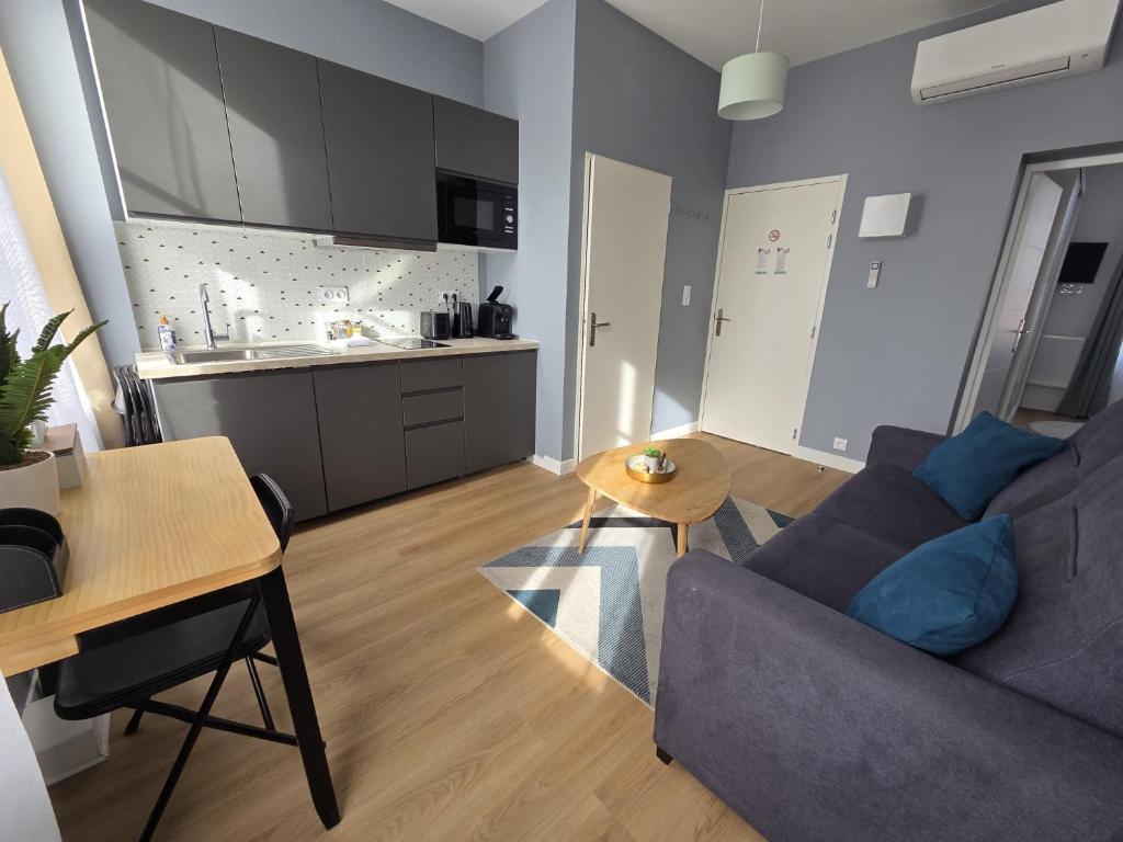 a living room with a couch and a table and a kitchen at G4 - Appartement 2 ch Climatisé Centre Angoulême in Angoulême