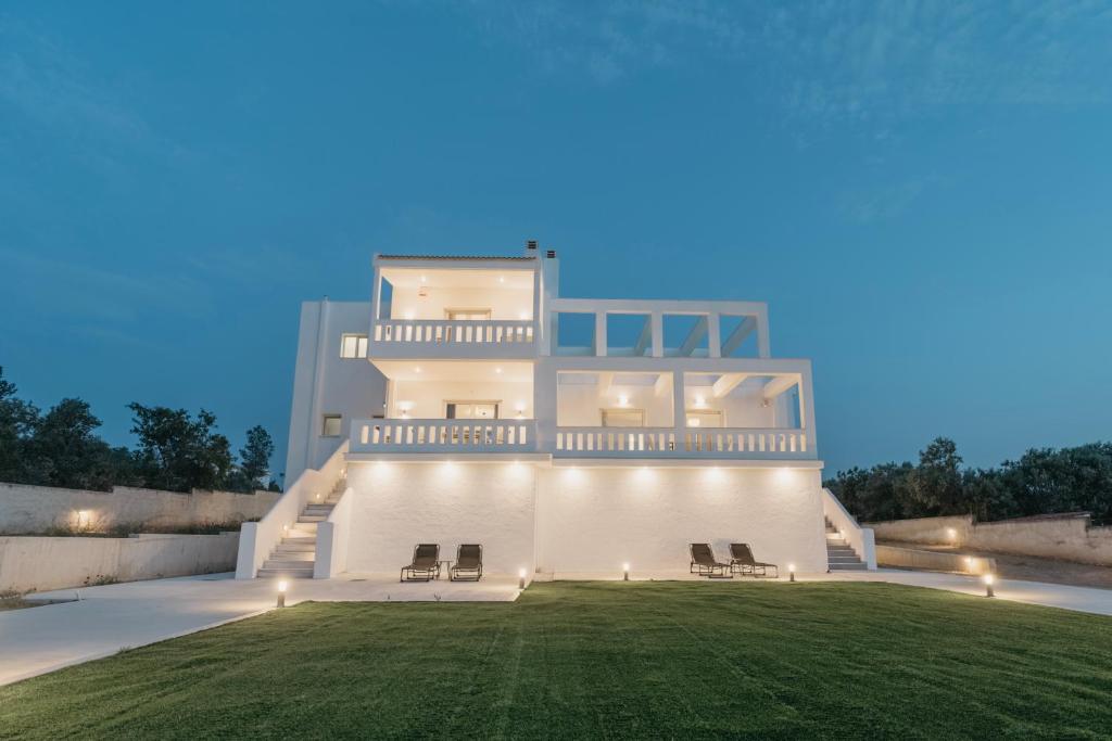 a white house with a lawn in front of it at Areti White Villas in Loutraki