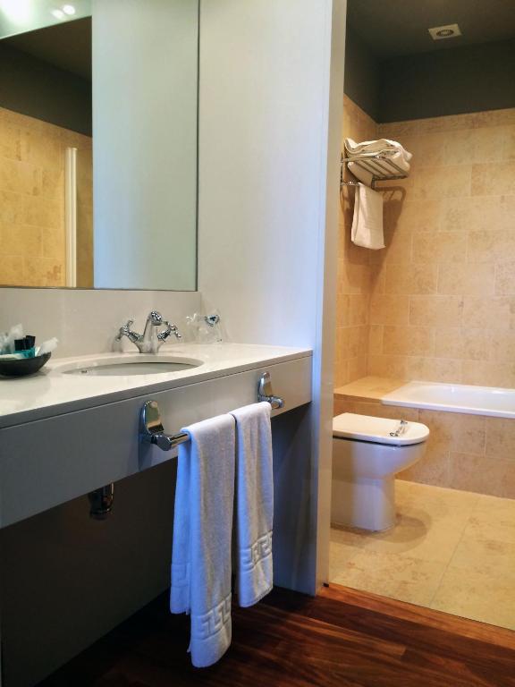 Un baño con lavabo, inodoro y espejo. en Hotel Vinícola Real-200 Monges, en Albelda de Iregua