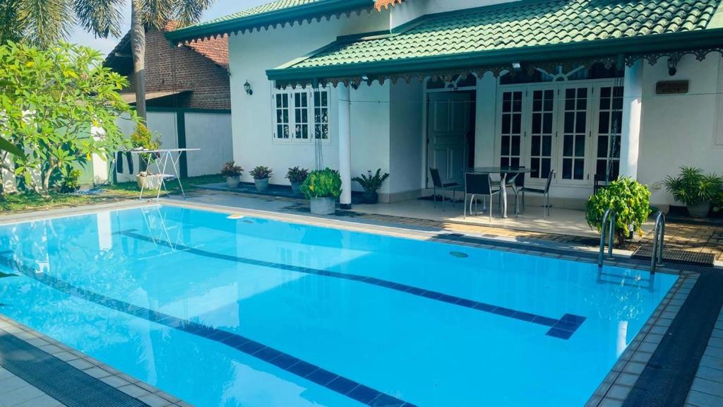 a large blue swimming pool in front of a house at Eco Villa Resort in Negombo