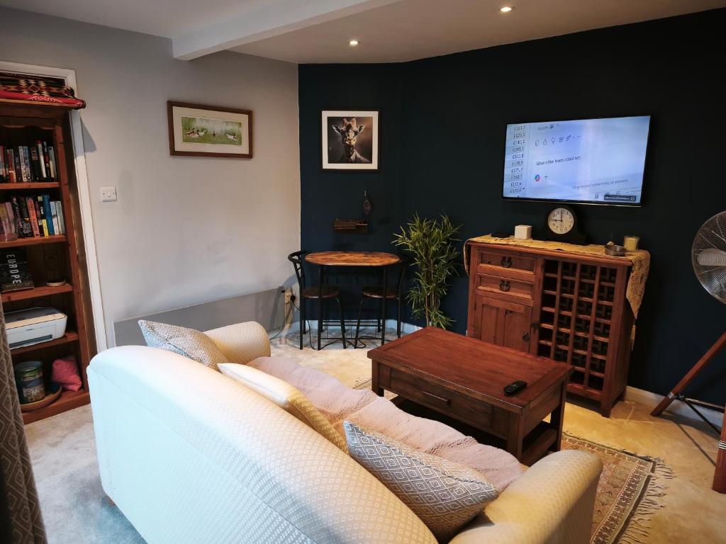 a living room with a couch and a tv on a wall at Groombridge 1 Bed self catered flat, can sleep 2 in Groombridge