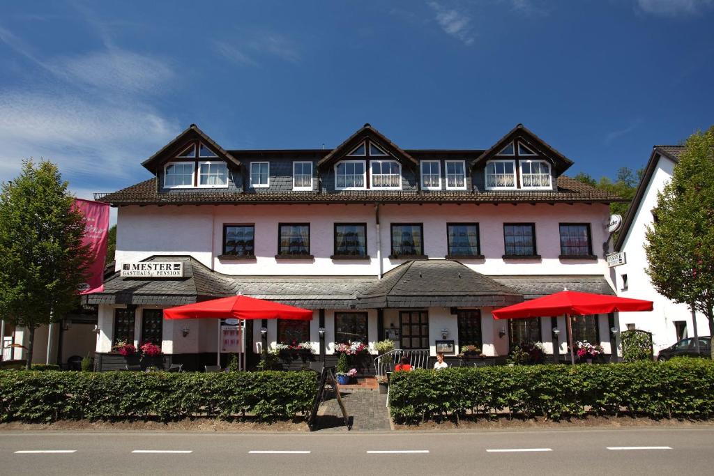 un gran edificio con sombrillas rojas delante en Gasthaus Mester, en Oedingen