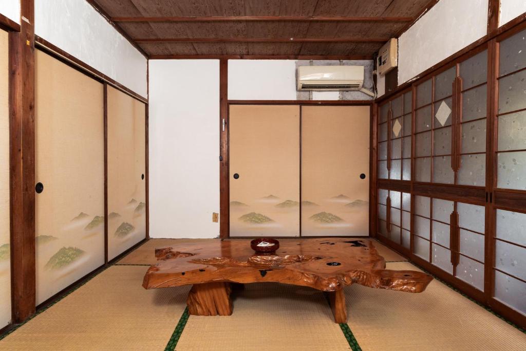 a room with a wooden table in a room with glass doors at FLORAhouse in Oita