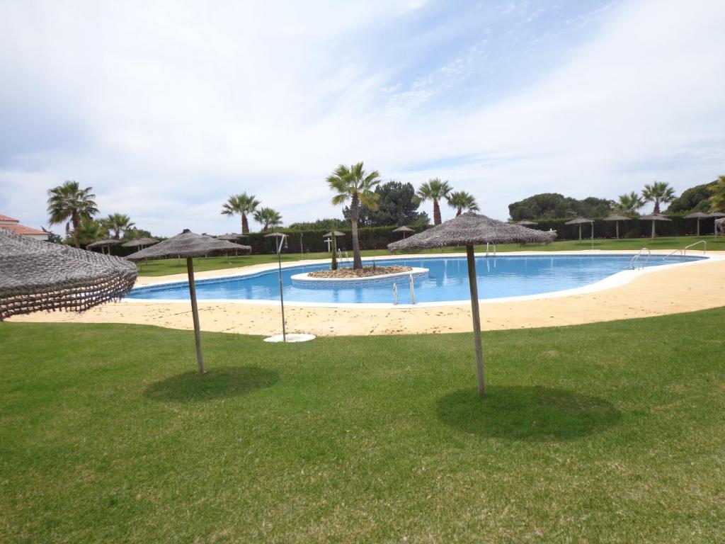 - une piscine avec parasols et une plage dans l'établissement Disfruta del paraíso en primera línea de playa con Kayak y Paddle Surf, à El Rompido