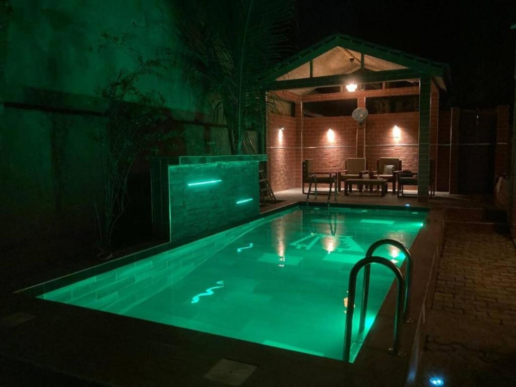 a swimming pool with green lighting in a house at night at Tekrour- la case des hôtes- Suite privée-chambre, salon et cuisine complete in Mbour