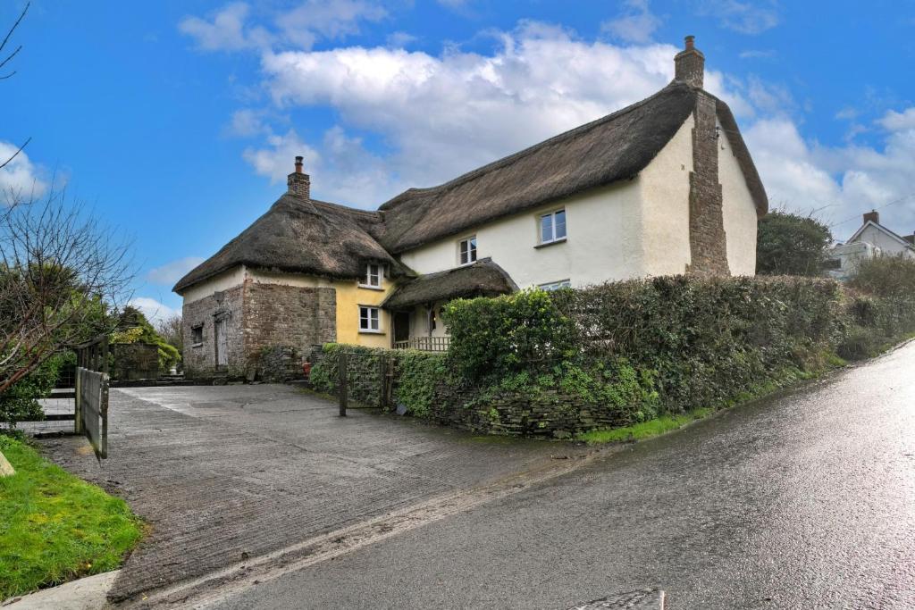 a large white house with a thatched roof at Finest Retreats - Syncocks Farm Cottage in Petrockstow
