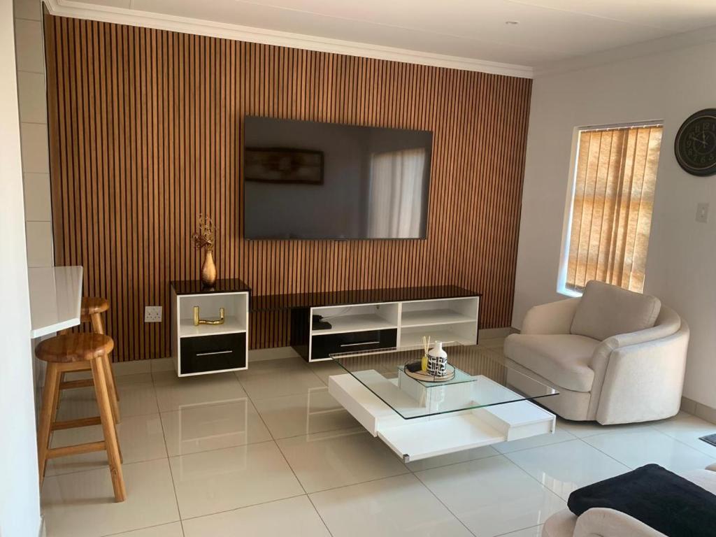 a living room with a television and a couch and a table at The Pebbles-UB in Mahikeng