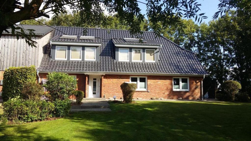 a red brick house with a black roof at Ferienhaus - Kann in Vollerwiek