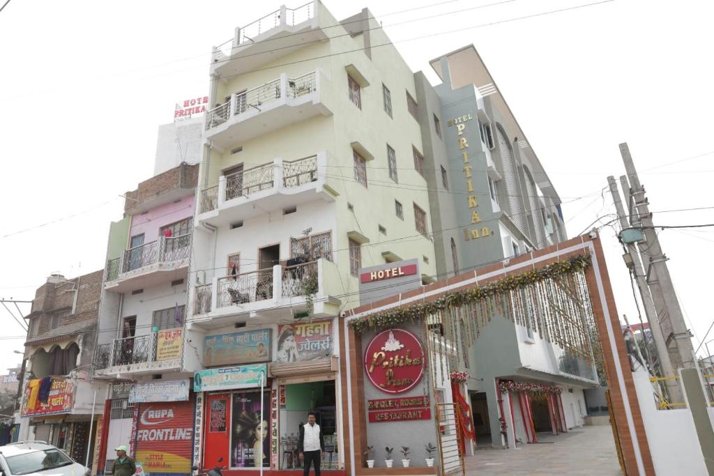 a tall white building on a street with shops at Hotel Pritika Inn in Samastīpur