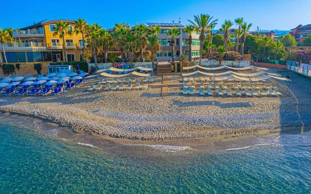a beach with chairs and umbrellas on the water at CLUB MONTE CARLO HoTEL in Alanya