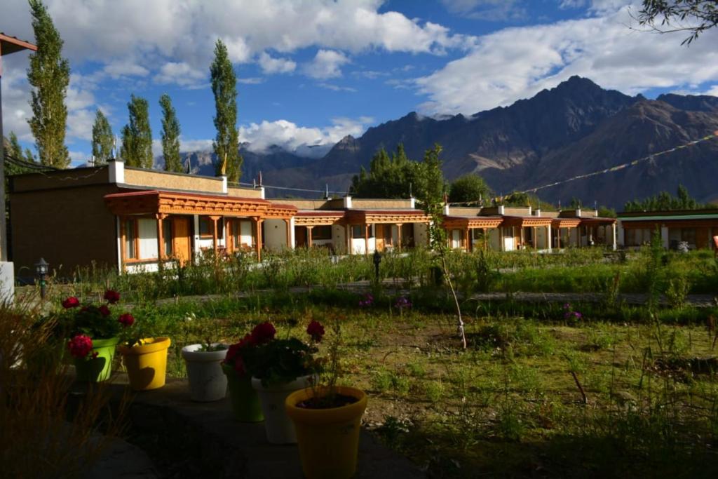 a house with flowers in a yard with mountains in the background at The Walnut Inn Resort in Hundar