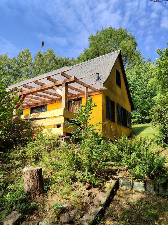 a small yellow house with a wooden roof at Berghütte am Grenzwinkel in Sebnitz