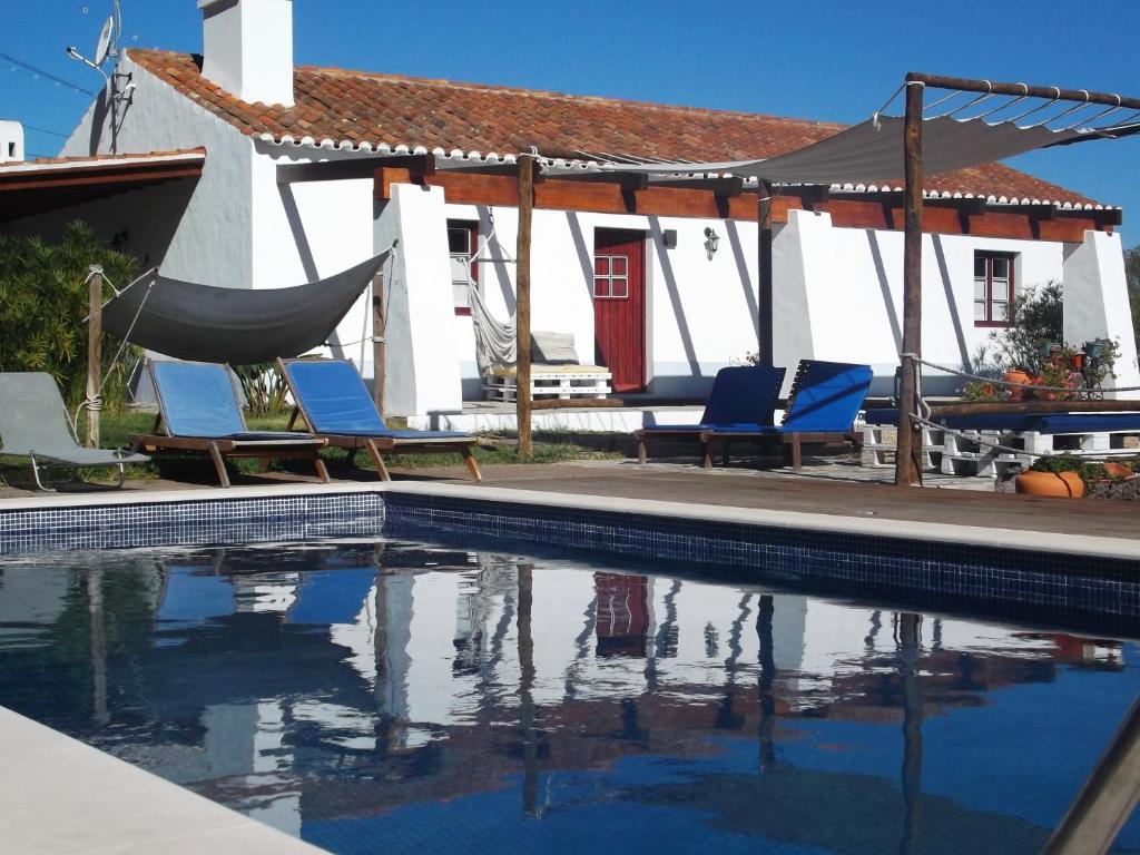 einen Pool mit Stühlen und einer Hängematte neben einem Haus in der Unterkunft Courela do Salgueiro in Carocha