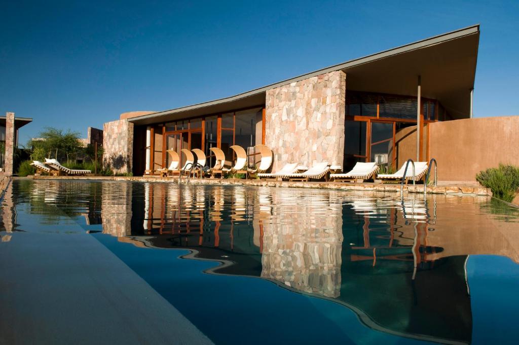 a building with chairs and a pool of water at Tierra Atacama Hotel & Spa in San Pedro de Atacama