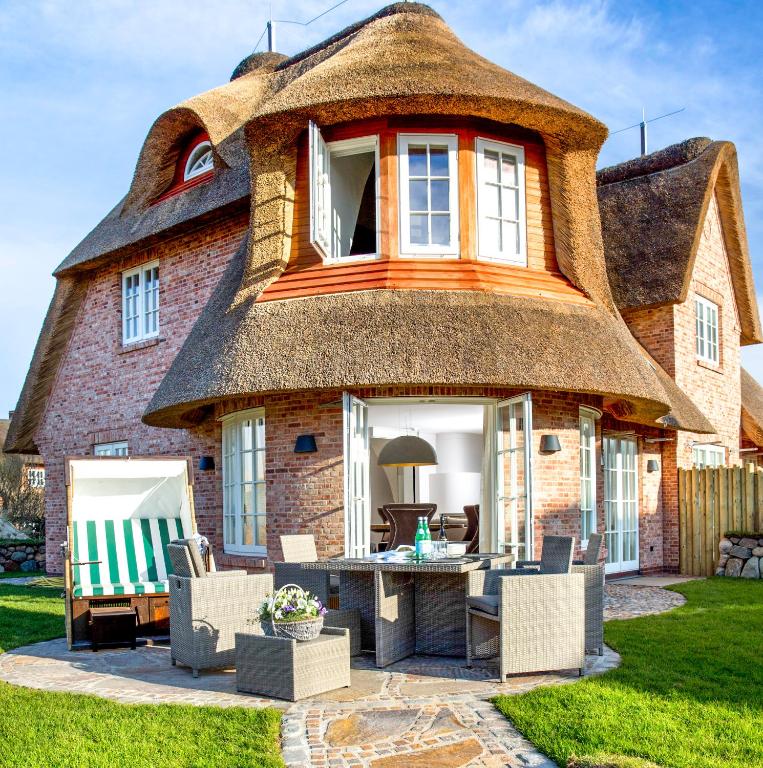 a thatched house with a table and chairs in front at Rantum Lodge in Rantum