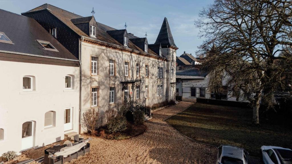an old stone building with a tree and a yard at Hotel Château Palacio in Fauvillers