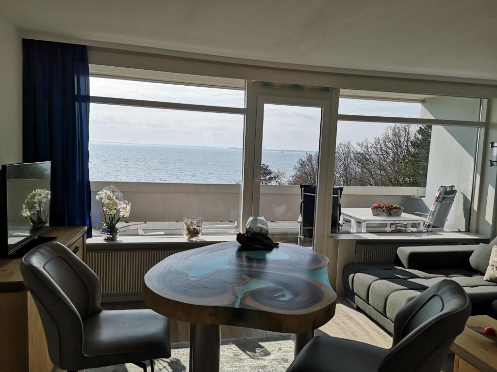 a living room with a table and a view of the ocean at Meerblick 1 in Sierksdorf