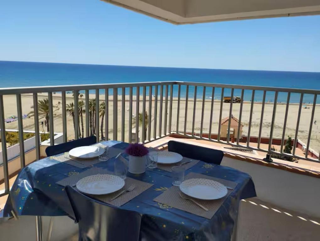 a table on a balcony with a view of the beach at Apartamento con vistas al mar! Comaruga in La Playa