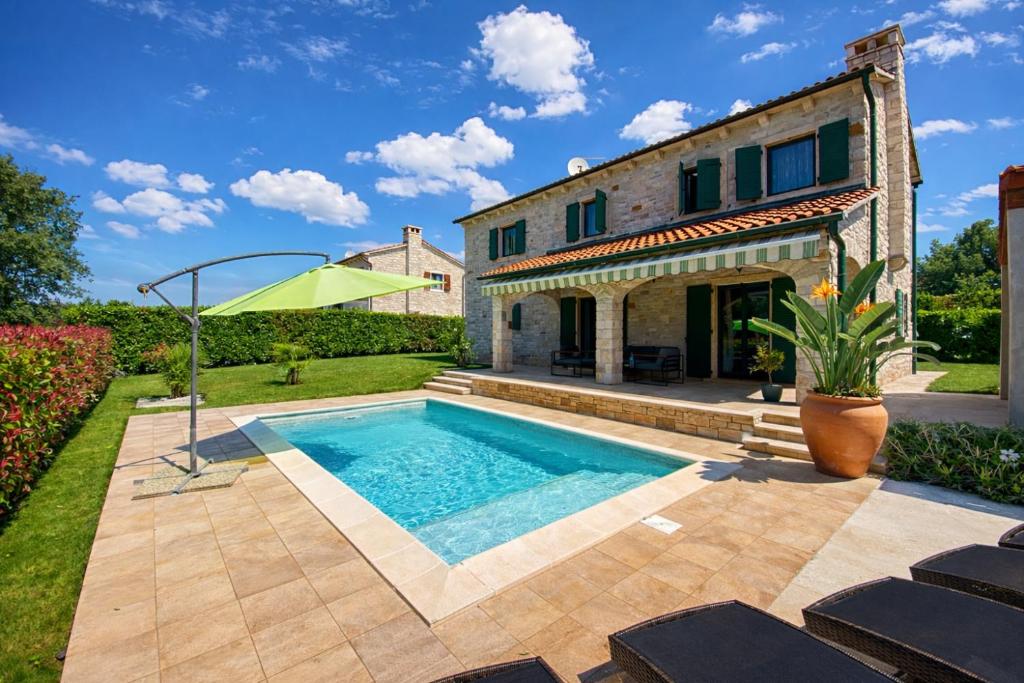 a house with a swimming pool in the yard at Villa Dracena mit privatem Saltwater Pool in Višnjan