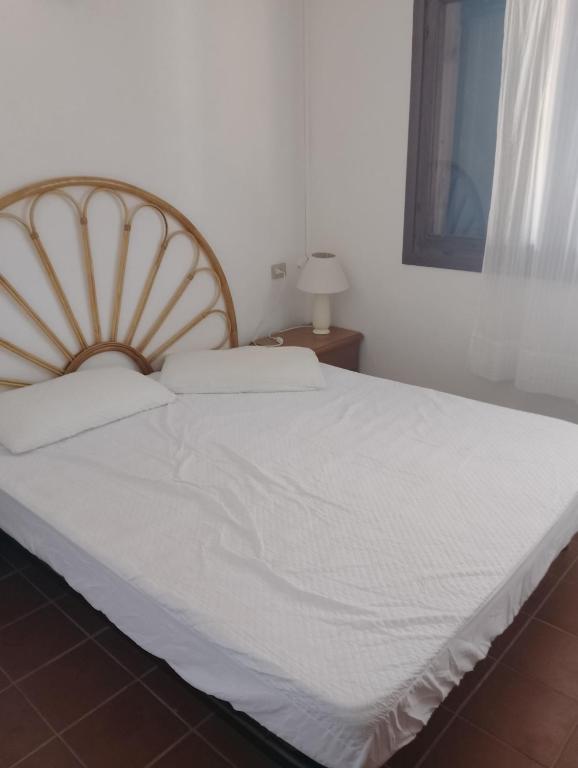 a bedroom with a white bed with a wooden headboard at Residence Costa Caddu San Teodoro in Porto Ottiolu