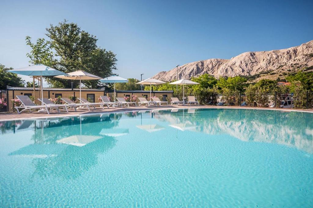 a large swimming pool with chairs and umbrellas at Camping Baska in Krk