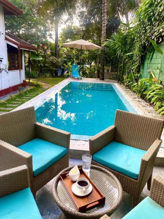 a pool with two chairs and a table with a table at Colonial Boutique Villa Kandy in Kandy
