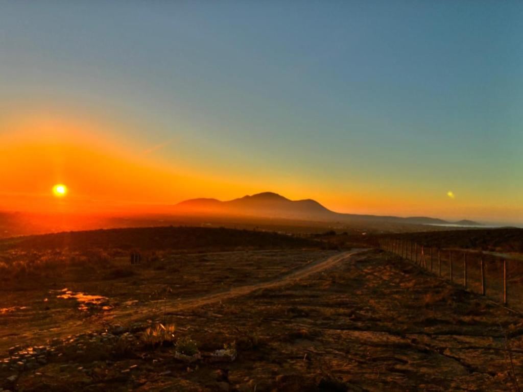 a sunset over a field with a dirt road at Katarina Logde en la naturaleza in Tongoicillo