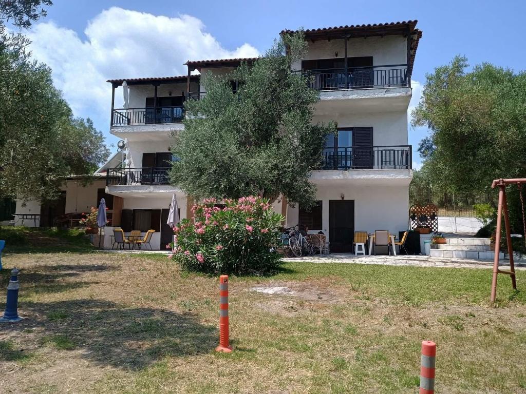 a large white building with tables and chairs in a yard at Vila Vergina in Pefkochori