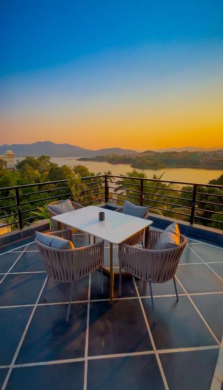 a table and chairs on a balcony with the sunset at Saga by Lake in Udaipur