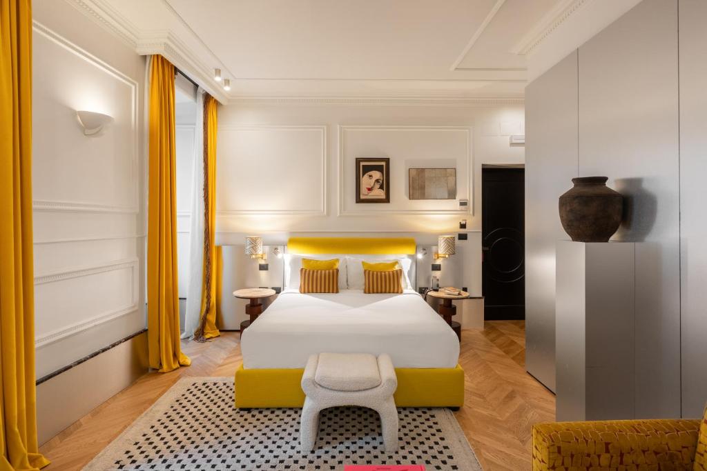 a bedroom with a white bed and yellow curtains at The Couper Umiltà in Rome