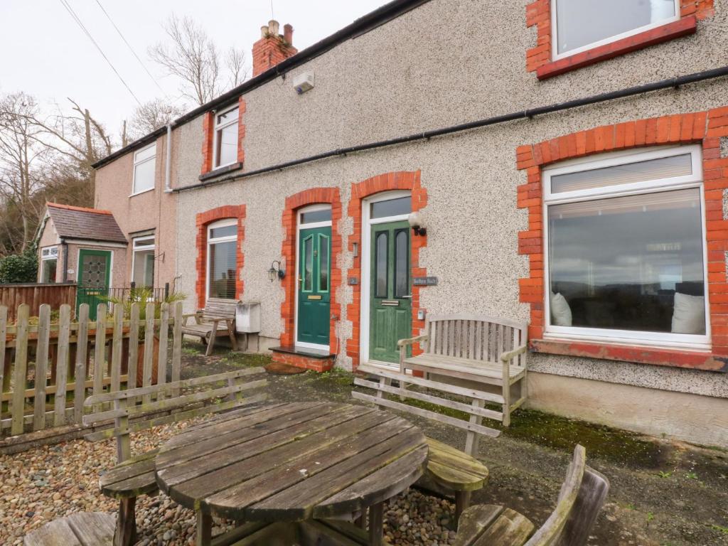 a wooden table in front of a house with a fence at 3 Bay View Terrace in Llandudno